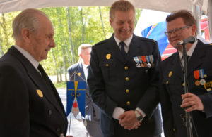 Kunniajäsen Veikko Linnus sai palokunnan ensimmäisen standaarin puheenjohtaja Ari Nummelta (kesk) ja päällikkö Kimmo Jäppiseltä.