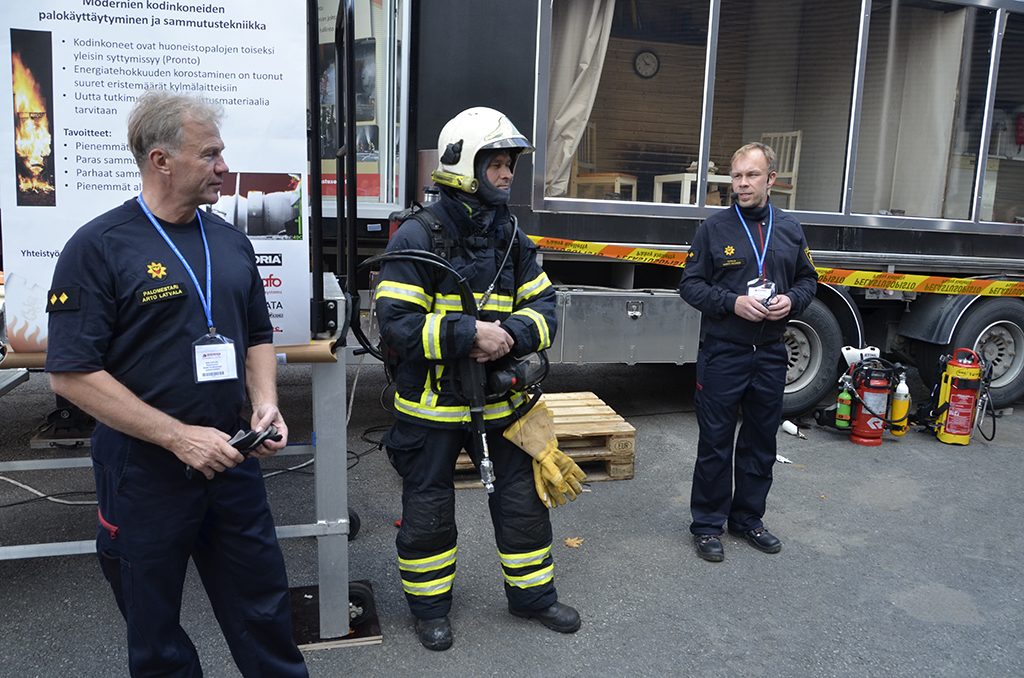 Palomestari Arto Latvala, yliopettaja Ismo Huttu ja tutkija Marko Hassinen demonstroivat turvallisuusmessuilla kodinkoneiden tulipaloja.