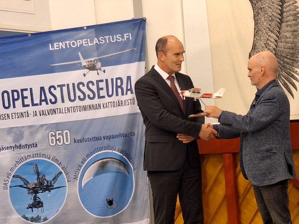 Sisäministeriön kansliapäällikkö Matti Sarasmaa piti juhlapuheen Suomen Lentopelastusseuran 20-vuotisjuhlass. Seuran puheenjohtaja Pekka Halme muisti juhlapuhujaa lentokoneella.