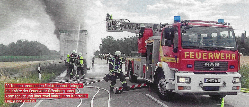 Palokunta rajoittaa SER-romukuorman paloa suihkuputkella ja tikasauton vesitykillä. Kuvakaappaus: Feuerwehr-Magazin 9/2025.